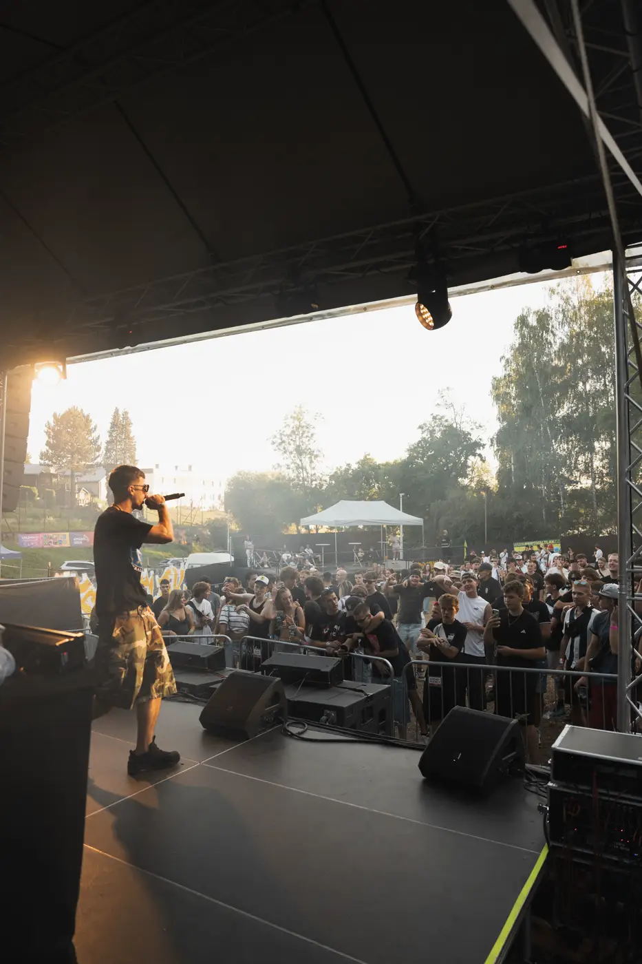 Festival TLAK 2026 — Pohled z boku pódia na interpreta a dav