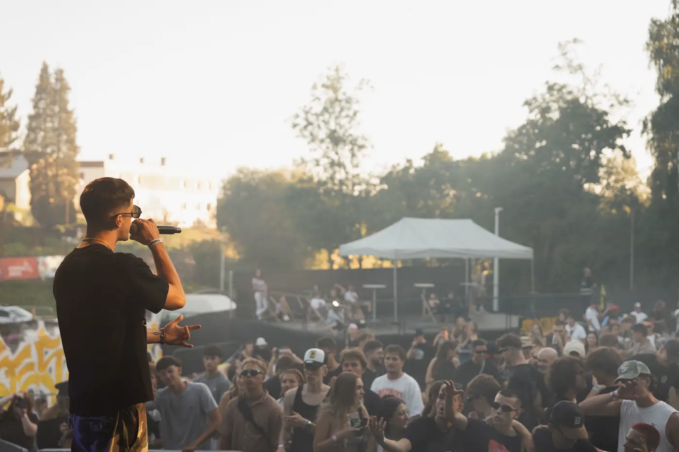 Festival TLAK 2026 — Rapper zády k objektivu a dav v protisvětle
