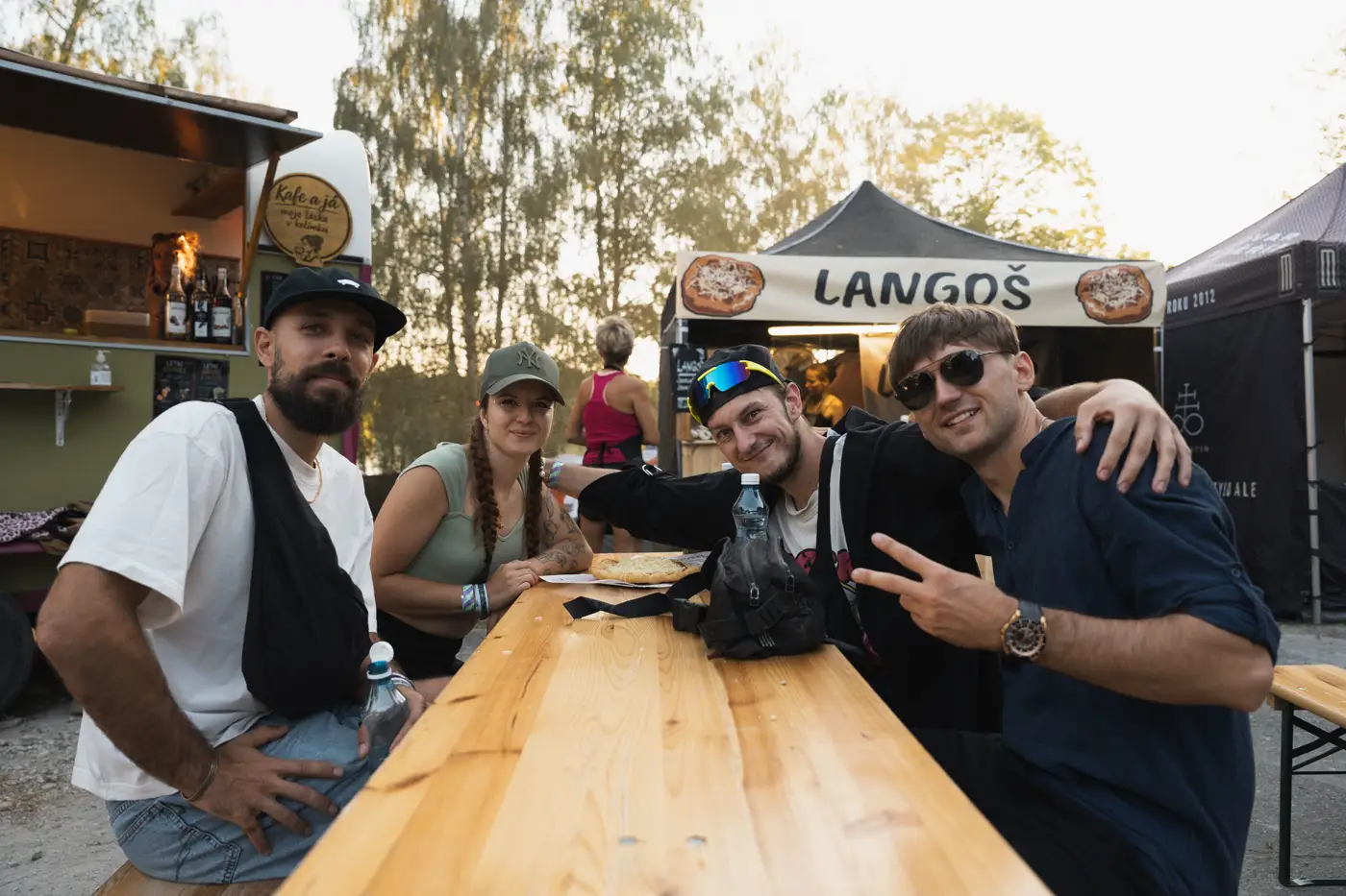 Festival TLAK 2026 — Návštěvníci u dřevěného stolu ve food zóně
