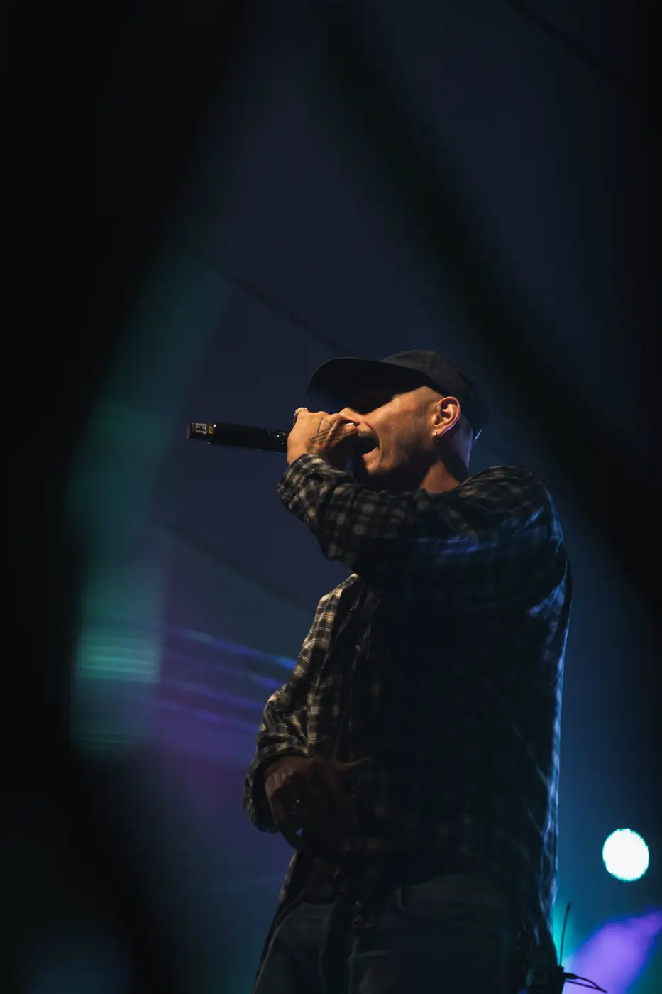 Festival TLAK 2026 — Rapper s mikrofonem v modrém světle