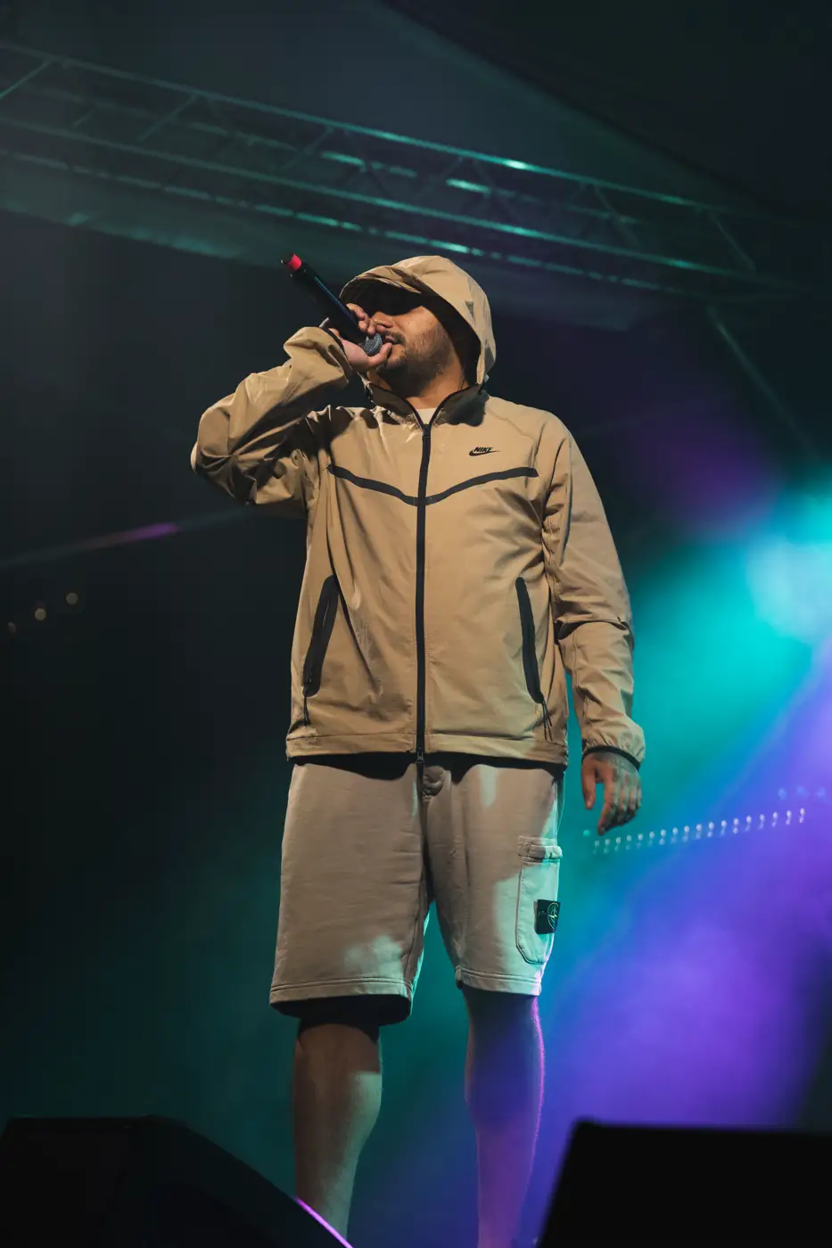 Festival TLAK 2026 — Interpret na pódiu v modrozelených světlech