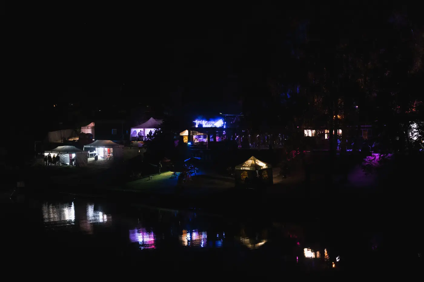 Festival TLAK 2026 — Noční panorama festivalového areálu u vody