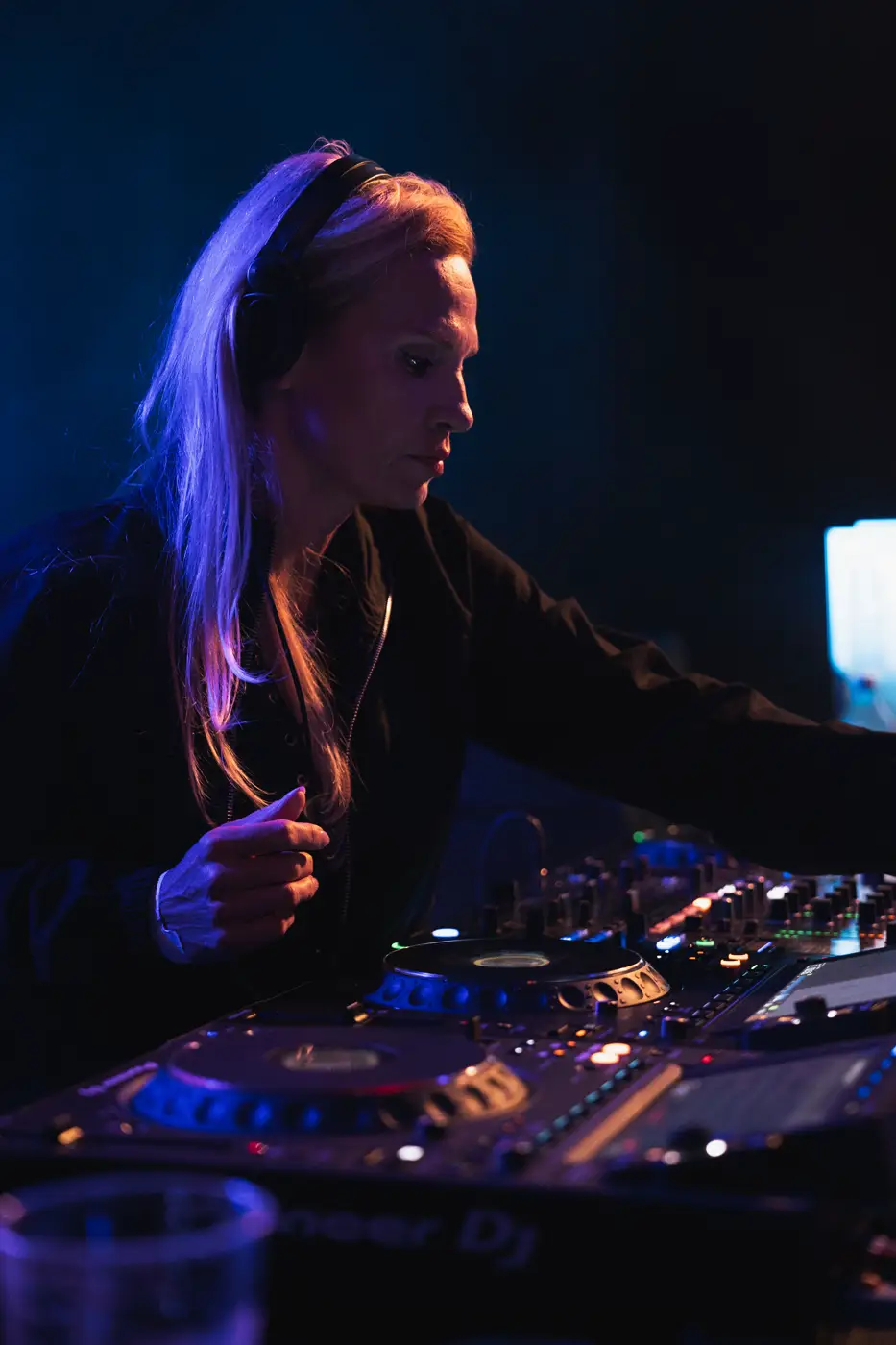 Festival TLAK 2026 — DJka za pultem v modrém světle